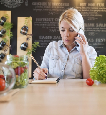 restaurant staff sitting at table on cell phone taking notes