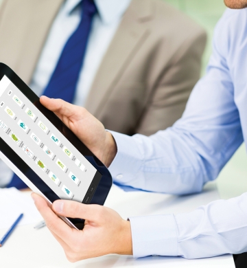 man holding tablet showing stats to man sitting next to him